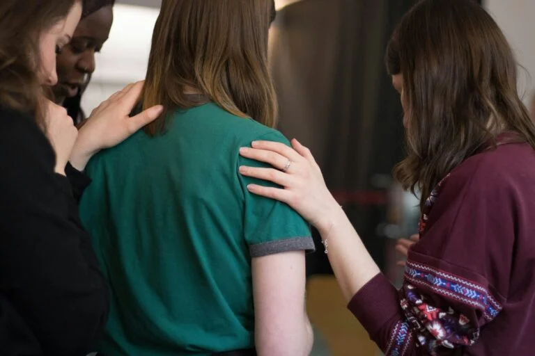 Church friends with their arms around each other in prayer