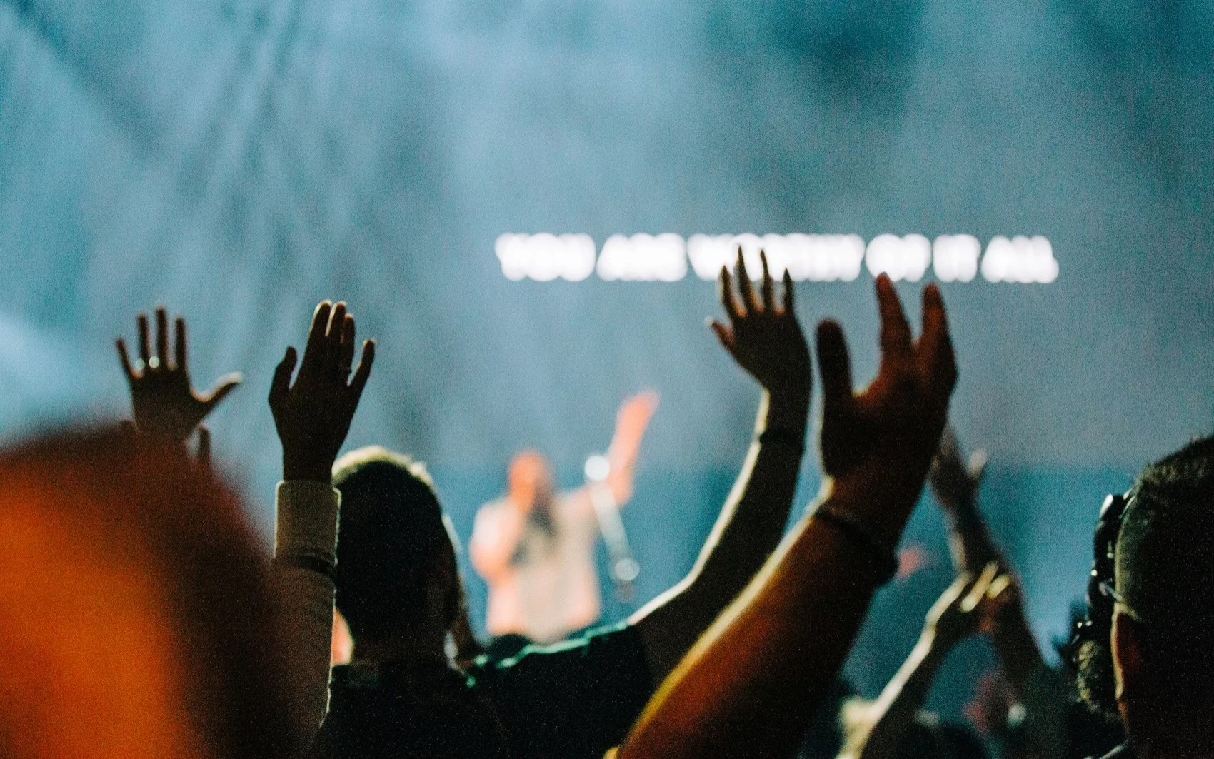 People with hands raised in worship during a night service