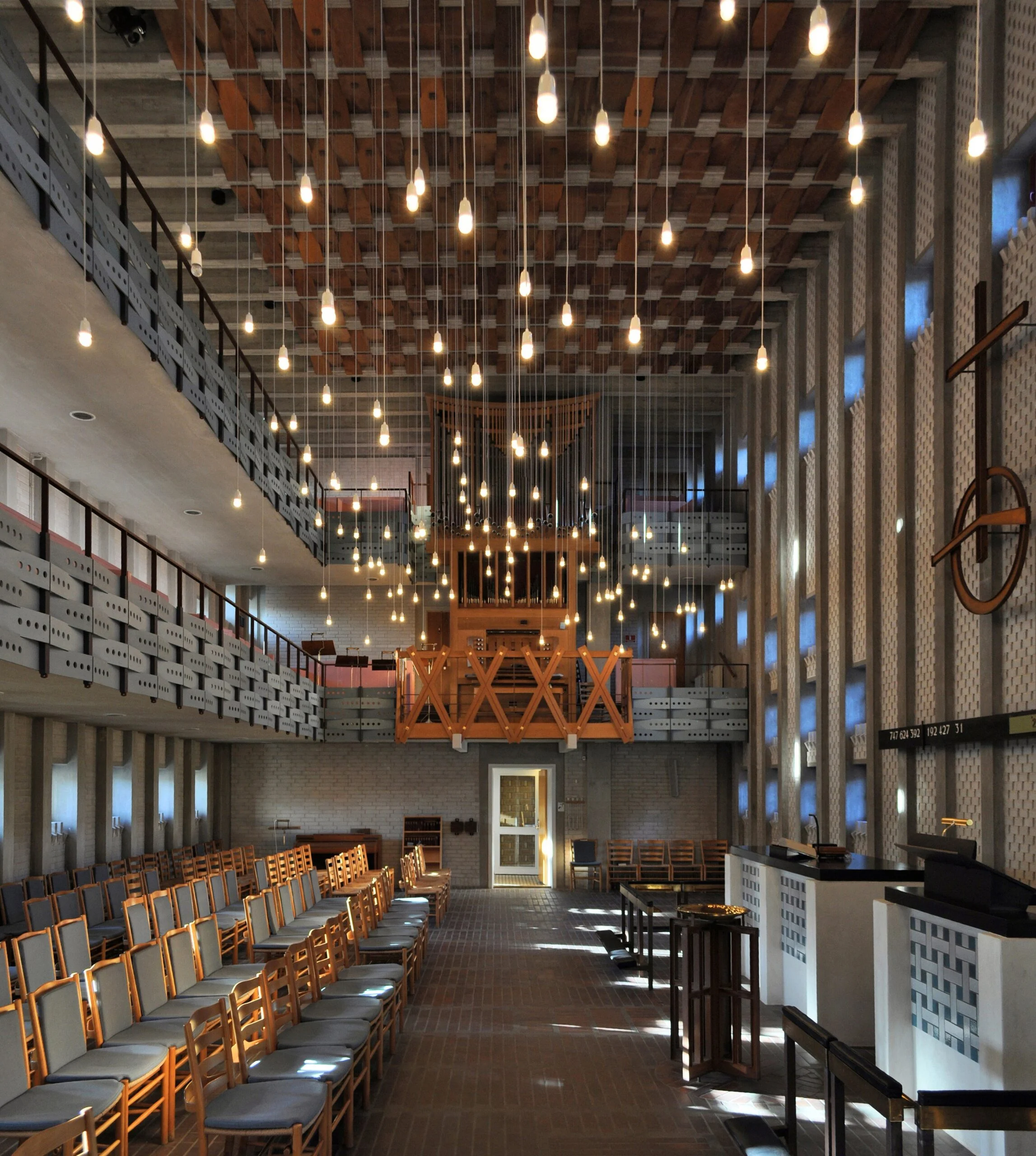 Long church interior with hundreds of hanging lights and wooden chairs